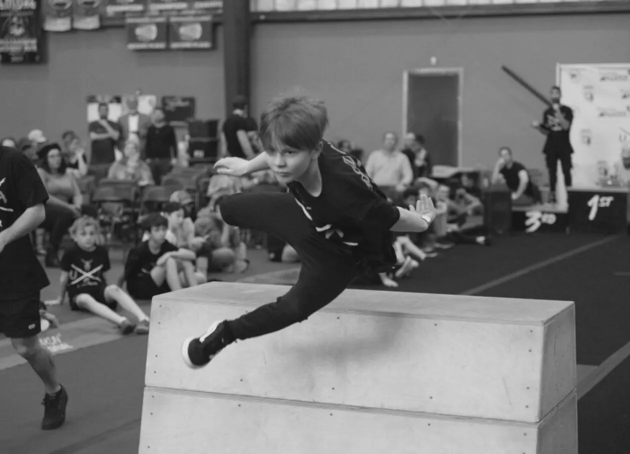Young person climbing outdoor bars during a parkour event